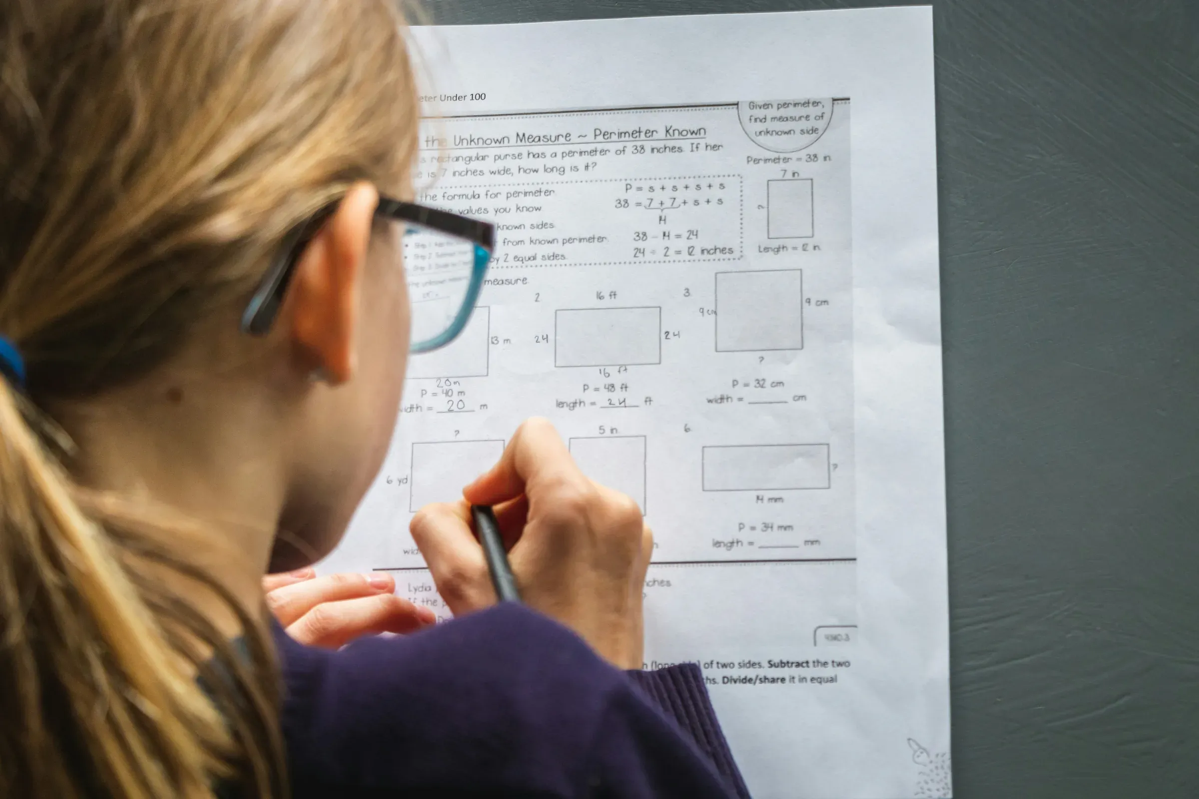 A student working through a worksheet at a desk