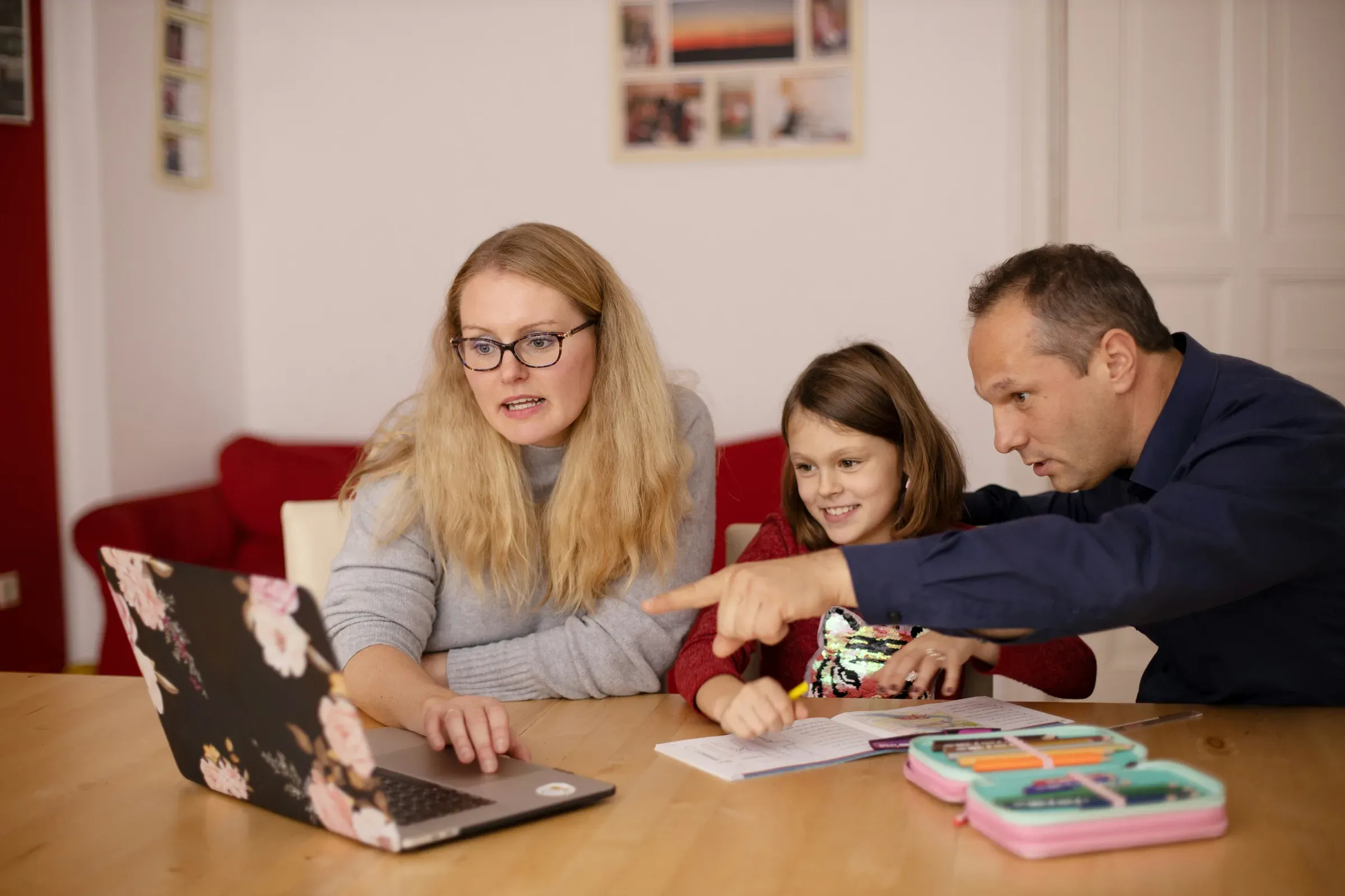 Two parents and their child working together at a laptop at home