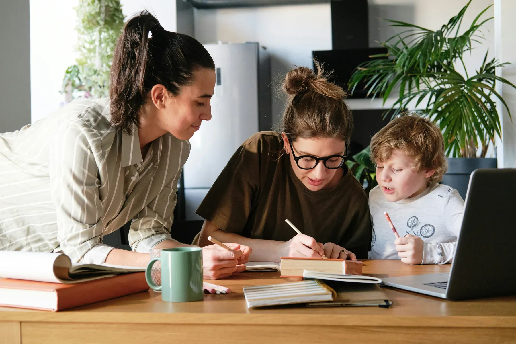 Two adults going over notes and paperwork at a table with a child alongside them