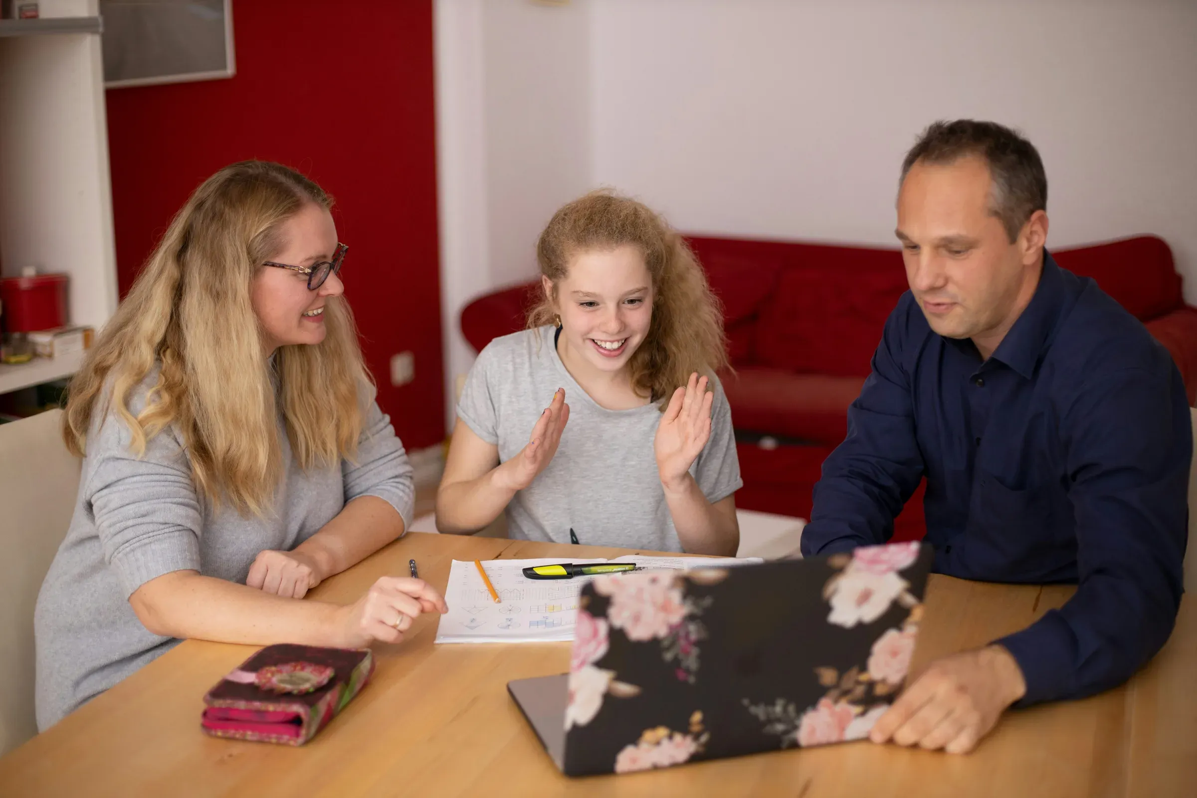 A happy young student doing schoolwork with her parents