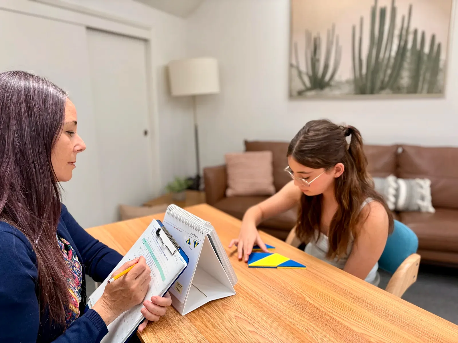 Erica Salzman and a student working on a shape puzzle at a testing table