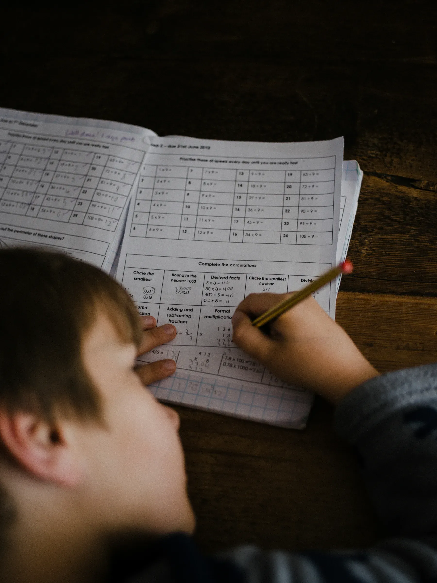 A child working through a writing task at a desk
