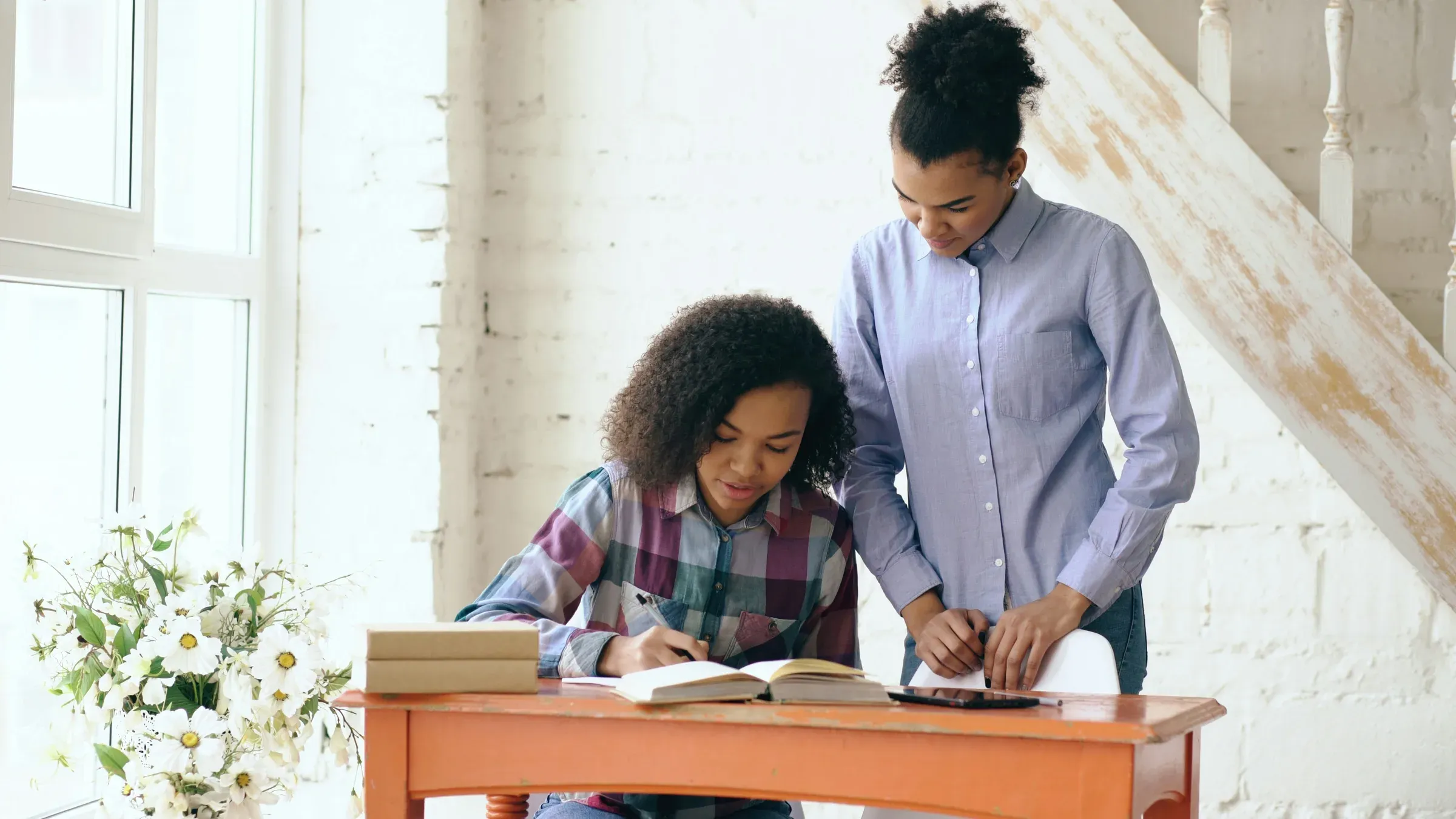 A mentor helping a student with schoolwork at a table