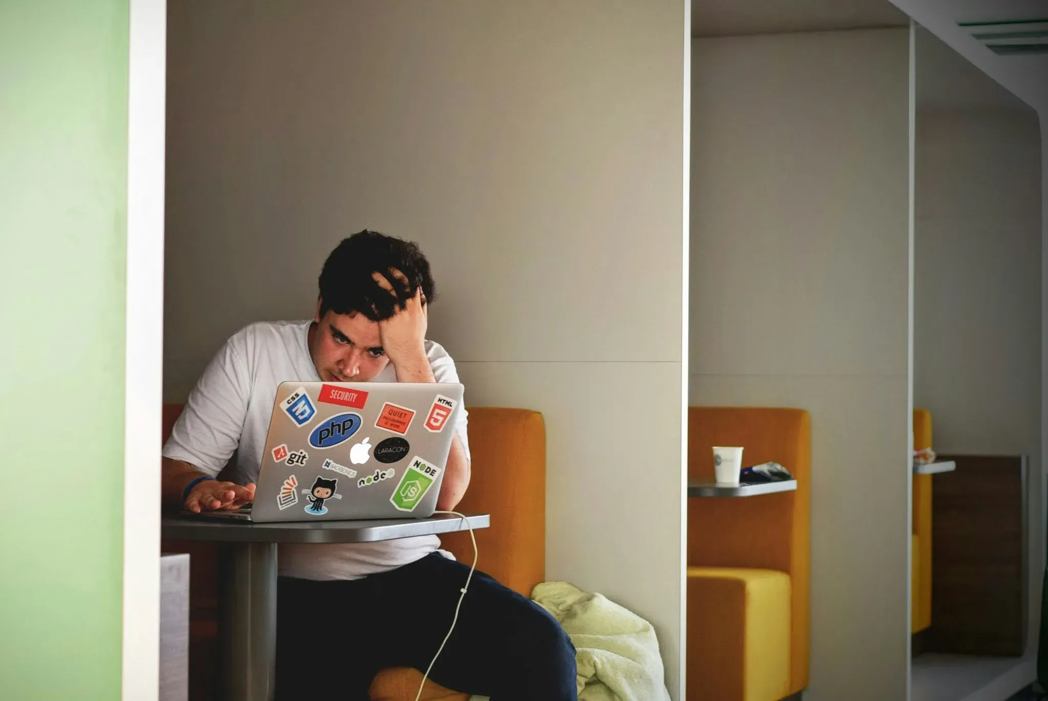 A person pausing, head in hand, while working at a laptop