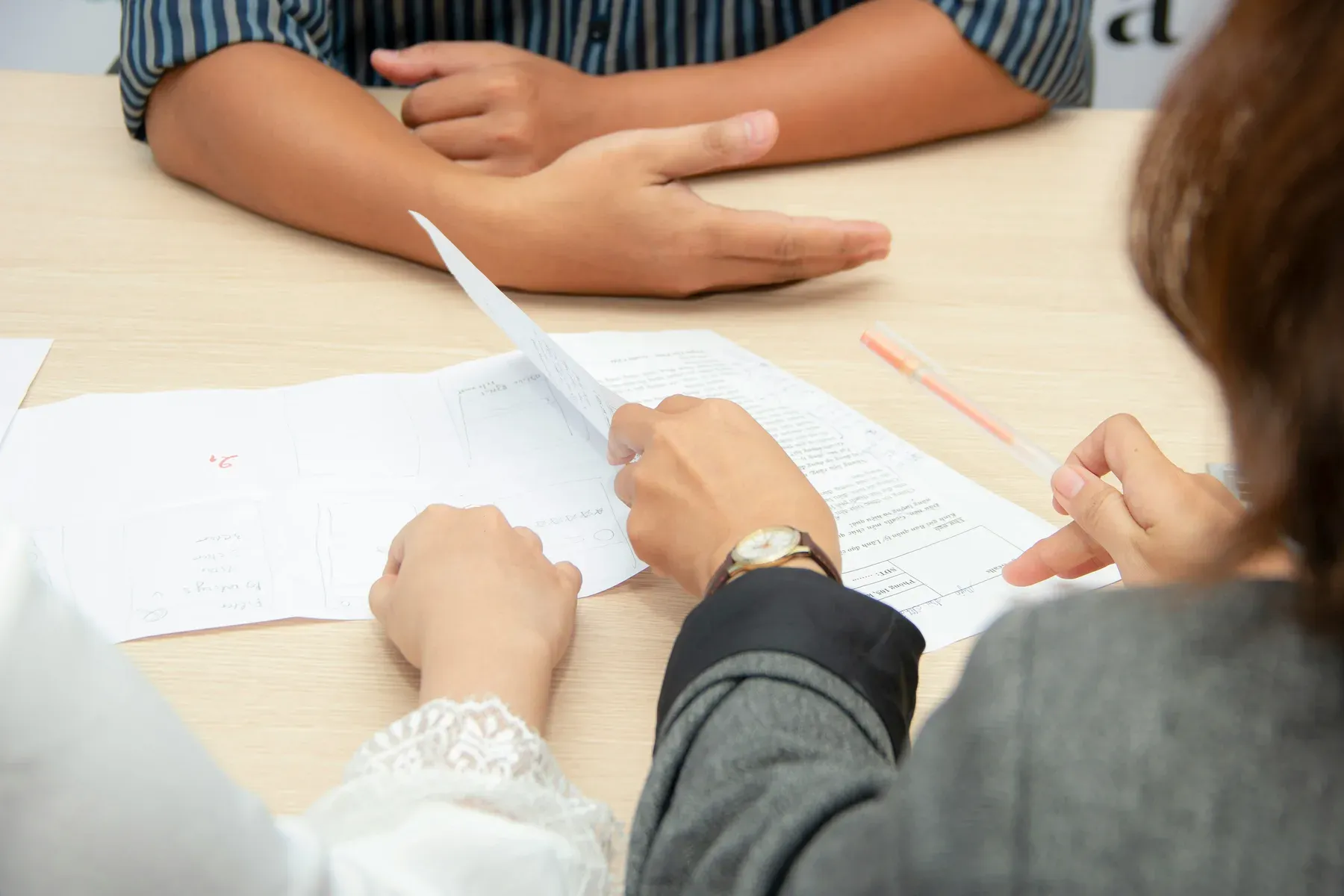 Two adults reviewing a printed document at a table, one pointing to a line on the page